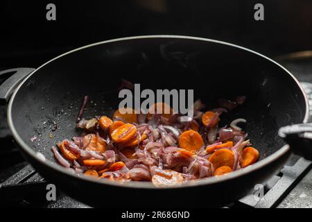 Les oignons et les carottes sont frits dans une poêle à frire profonde. Préparation de la cuisson. Banque D'Images