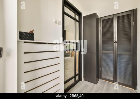 une entrée avec des volets noirs et blancs sur les portes, parquet et lattes en bois Banque D'Images