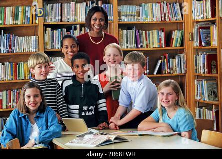 Portrait d'un bibliothécaire afro-américain de l'école élémentaire dans la bibliothèque de l'école avec un groupe d'élèves de race mixte Banque D'Images