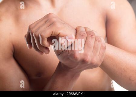 Mains de l'homme au foyer, l'une saisissant le poignet de l'autre en raison de la douleur, peut-être tendinite ou syndrome du canal carpien Banque D'Images