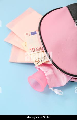 Sac cosmétique pour dames avec coupe menstruelle, coussinets et argent sur fond bleu Banque D'Images