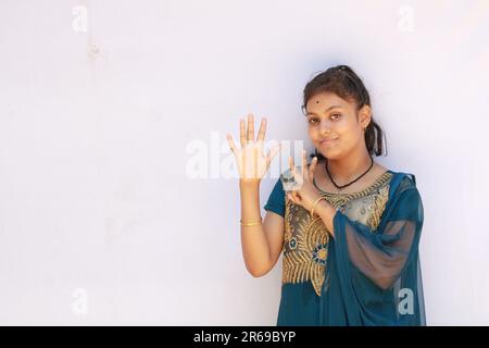 Portrait de la belle adolescente indienne heureuse montrant et pointant avec le doigt numéro huit tout en souriant confiant et heureux. Banque D'Images