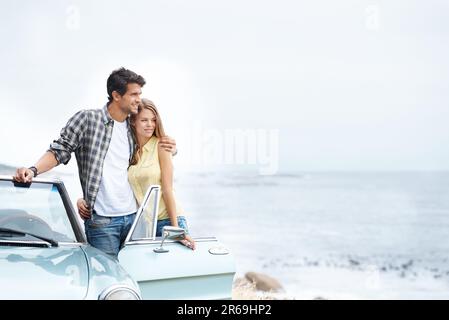 Profitez d'une vue magnifique. Un jeune couple romantique debout à côté de leur cabriolet pendant un voyage. Banque D'Images
