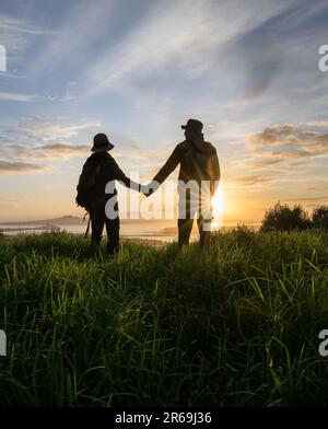 Couple debout sur le sommet du Mont Eden et regardant l'île Rangitoto au lever du soleil. Auckland. Format vertical. Banque D'Images