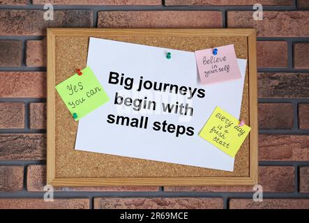 Tableau de bord avec citations motivationnelles sur le mur de brique Banque D'Images