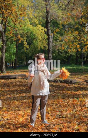 La photo a été prise dans le parc public d'Odessa appelé le jardin de Dyukovsky. Dans la photo, une fille en lunettes de soleil a mis ses paumes jusqu'au soleil d'automne dedans Banque D'Images