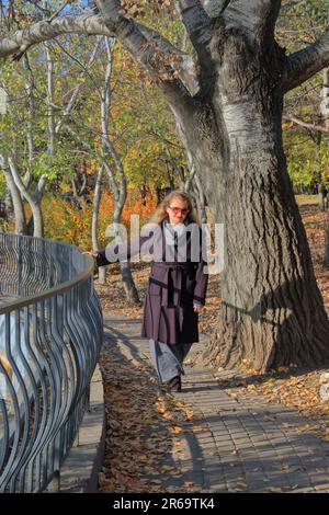 La photo a été prise dans le parc public d'Odessa appelé Victory Park. La photo montre une jeune femme marchant près du lac dans le parc d'automne. Banque D'Images