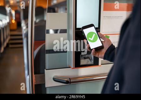 Personne achetant un billet de train avec un smartphone à partir d'une machine à billets. Tenir le téléphone avec la coche verte Banque D'Images