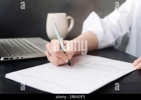 Femme d'affaires confiante signant le document officiel : la main de la femme avec stylo finalisant le papier de contrat, démontrant le professionnalisme et l'engagement dans Banque D'Images