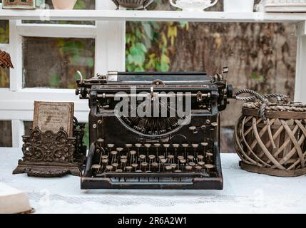 Machine à écrire vintage à l'ancienne sur un bureau en bois à côté de la fenêtre dans un blanc clair shabby chic vintage maison de campagne provençale Banque D'Images