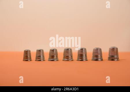 Gros plan de quelques cartouches de couture de différentes tailles alignées sur un arrière-plan orange et un espace de copie Banque D'Images