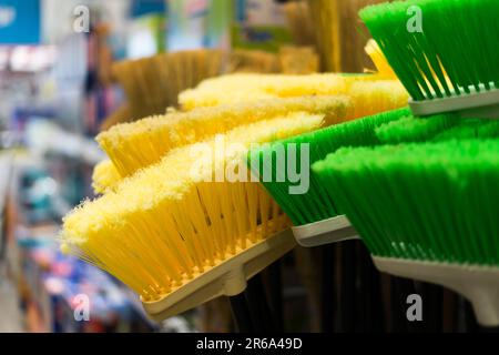 Brosses en plastique pour le nettoyage des locaux. Assortiment de balais multicolores dans le magasin. Gros plan Banque D'Images
