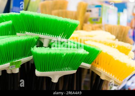 Brosses en plastique pour le nettoyage des locaux. Assortiment de balais multicolores dans le magasin. Gros plan Banque D'Images