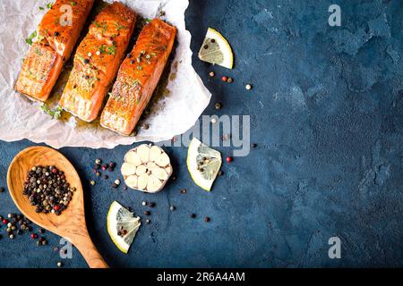 Délicieux filet de saumon frit avec assaisonnements sur fond de béton rustique bleu. Steak de saumon cuit au poivre, aux herbes, au citron, à l'ail, cuisson Banque D'Images