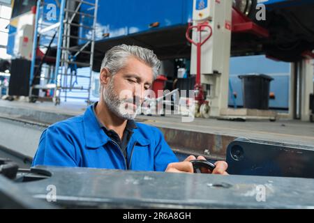 attrayant mécanicien portant une combinaison travaillant seul Banque D'Images