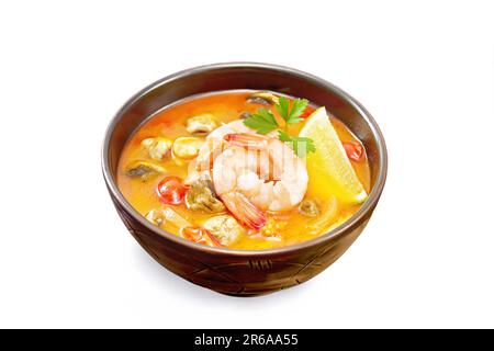 Soupe thaïlandaise Tom Yam de crevettes, viande de poulet aux champignons, tomates et citron dans un bol en argile isolé sur fond noir Banque D'Images