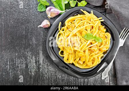 Spaghetti à la sauce à la crème de citrouille, oignon et ail dans une assiette, serviette, basilic et fourchette sur un fond de bois de dessus Banque D'Images