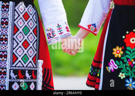 Filles en costumes traditionnels de l'ethnie bulgare avec le folklore broderie tenant les mains. L'esprit de la Bulgarie - culture, histoire et traditions. Banque D'Images