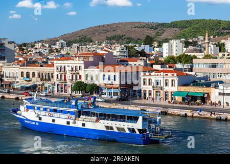 Vue sur la ville et le port de Chios, vue depuis un bateau. Un bateau touristique bleu a juste mis des voiles, comme il se produit pendant la saison d'été. Banque D'Images