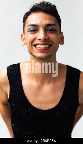 Portrait d'un homme transgenre biracial heureux portant un maquillage, souriant sur fond blanc Banque D'Images