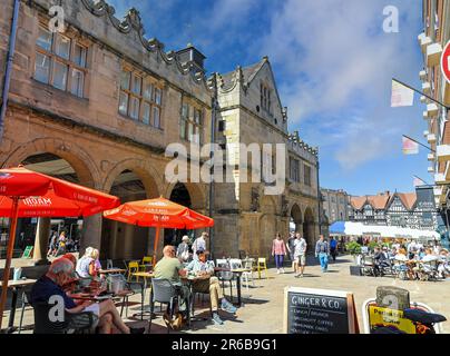 Les gens assis manger et boire à l'extérieur de l'Old Market Hall dans le centre-ville, Shrewsbury, Shropshire, Angleterre, Royaume-Uni Banque D'Images