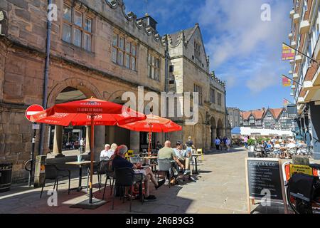 Les gens assis manger et boire à l'extérieur de l'Old Market Hall dans le centre-ville, Shrewsbury, Shropshire, Angleterre, Royaume-Uni Banque D'Images