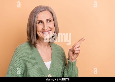 Photo de la femme d'affaires à la retraite porter gilet tendance main mockup regarder les nouvelles intéressées modèle isolé sur fond beige couleur Banque D'Images