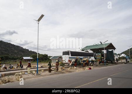 Tanzanie, Afrique - 14 mars 2023: Les vendeurs de femmes vendant des paniers faits à la main faucent leurs marchandises à un bus sur le côté de l'autoroute Banque D'Images