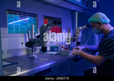 Biologiste menant des recherches sur le microscope en clinique Banque D'Images