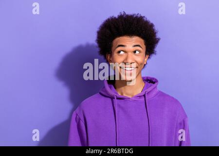 Portrait de jeune homme beau porter violet branché sweat à capuche sourire look pensif espace vide rêve isolé sur fond violet couleur Banque D'Images