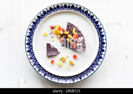 Croustilles croustillantes de tortilla au maïs bleu nappées de salsa fraîche. Banque D'Images