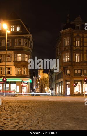 Kaiserslautern, Allemagne - 16 mars 2021: Stiftskirche, Collégiale, derrière des bâtiments à Kaiserslautern, Allemagne, pendant une nuit d'hiver. Banque D'Images