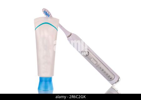 Un tube en plastique de dentifrice et un écran dentaire électrique, macro, isolé sur fond blanc. Banque D'Images