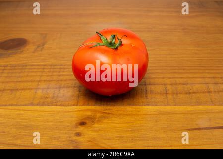 Goiania, Goias, Brésil – 08 juin 2023 : une grande tomate fraîche et mûre sur une surface en bois. Banque D'Images