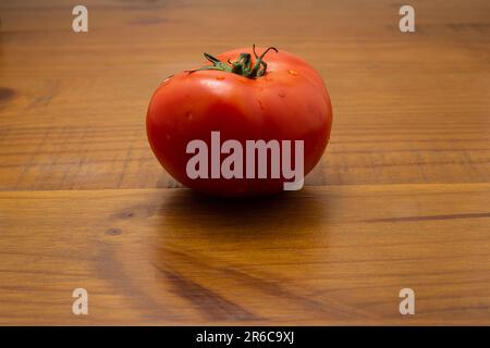 Goiania, Goias, Brésil – 08 juin 2023 : une grande tomate fraîche et mûre sur une surface en bois. Banque D'Images