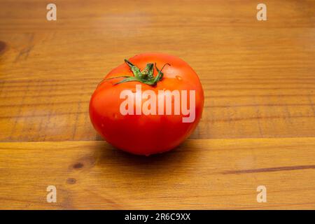 Goiania, Goias, Brésil – 08 juin 2023 : une grande tomate fraîche et mûre sur une surface en bois. Banque D'Images