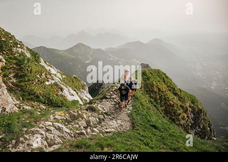 Un groupe de randonneurs se rend sur un sentier escarpé à flanc de colline, naviguant avec soin dans leur descente Banque D'Images