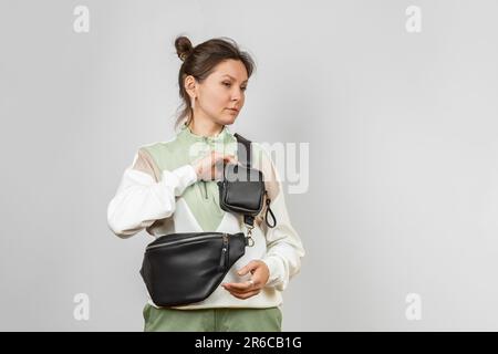 Femme portant un sac de taille en cuir noir avec porte-monnaie amovible accessoire pour ranger des clés, des cigarettes ou des écouteurs fixés à la sangle, Studio Shot Banque D'Images