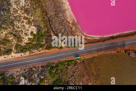 Pink Lake à Port Gregory en Australie occidentale, eaux colorées par des bactéries et des algues, beau contraste entre l'océan bleu et l'eau rose, nuages Banque D'Images