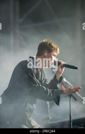 Un homme se tient sur une scène chantant passionnément dans un microphone tout en jouant un instrument de musique noir Banque D'Images