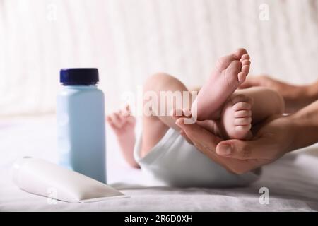 Mère tenant les jambes de bébé sur le lit, gros plan Banque D'Images