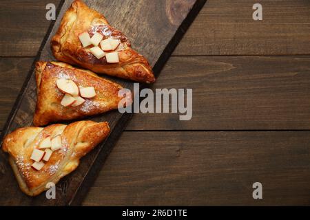 Pâte fraîche savoureuse avec sucre en poudre et pommes servies sur une table en bois, vue du dessus. Espace pour le texte Banque D'Images