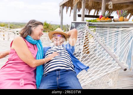 Couple caucasien âgé riant et allongé sur un hamac à la plage, copier l'espace Banque D'Images