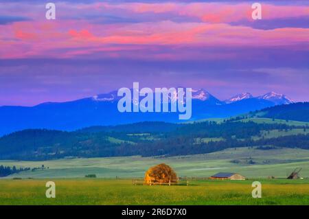 lever de soleil sur une botte de foin dans un pré au-dessous de la chaîne de floint creek près d'avon, montana Banque D'Images