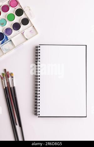 Gros plan de peintures, carnets et pinceaux avec espace de copie sur fond blanc. Retour à l'école, art, peinture, matériel scolaire, apprentissage, école et ed Banque D'Images