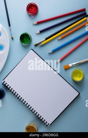 Gros plan de peintures, crayons, carnets et pinceaux avec espace de copie sur fond bleu. Retour à l'école, art, peinture, matériel scolaire, apprentissage, schoo Banque D'Images