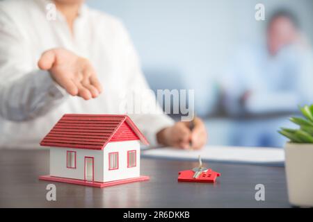 Femme d'affaires choisissant mini modèle de maison de modèle sur table en bois, planification pour acheter la propriété. Concept de choisir le meilleur. Banque D'Images