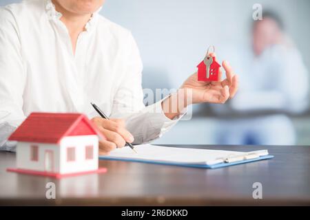 Femme d'affaires choisissant mini modèle de maison de modèle sur table en bois, planification pour acheter la propriété. Concept de choisir le meilleur. Banque D'Images