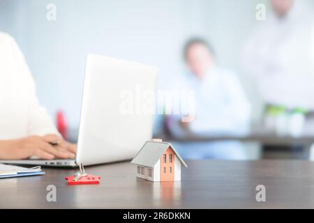 Femme d'affaires choisissant mini modèle de maison de modèle sur table en bois, planification pour acheter la propriété. Concept de choisir le meilleur. Banque D'Images