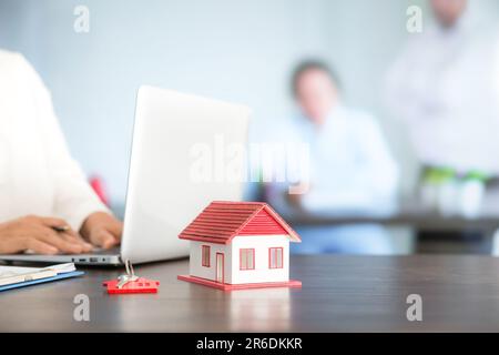 Femme d'affaires choisissant mini modèle de maison de modèle sur table en bois, planification pour acheter la propriété. Concept de choisir le meilleur. Banque D'Images